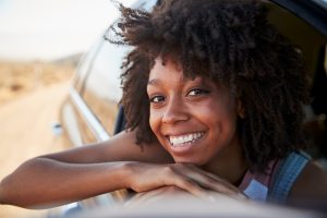 happy black woman leans out of a car window smiling after Cognitive behavioral therapy CBT in burke VA from a therapist at Nova Terra Therapy 22015