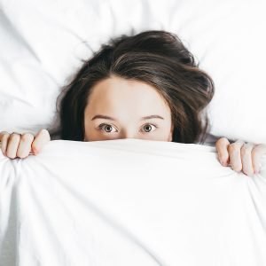 scared woman under the covers during coronavirus pandemic. She goes to online therapy in VA with Nova Terra Therapy 22015