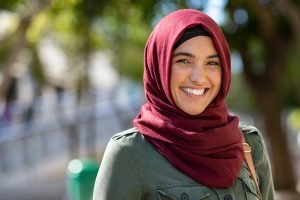 relieved woman smiles at the camera wearing a head covering. She gets trauma therapy and PTSD treatment at Nova Terra Therapy 22015